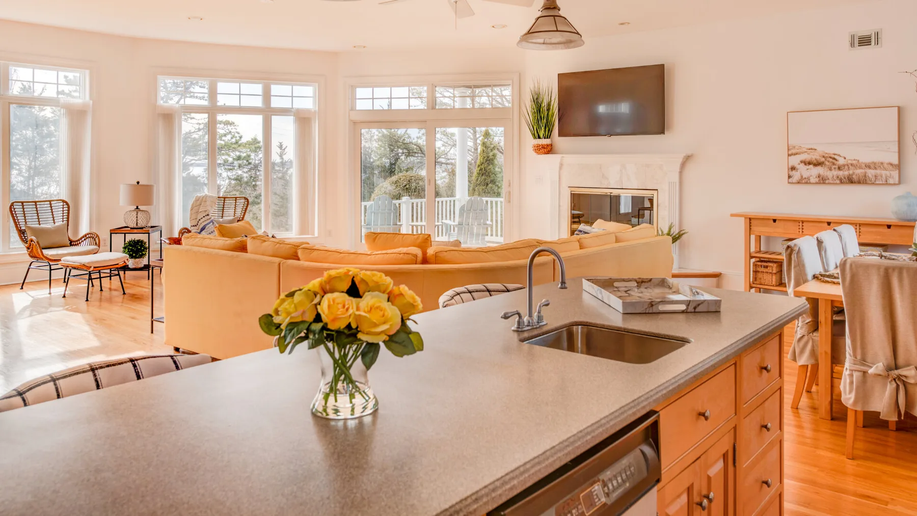 A bright open-plan living room and kitchen with large windows and a counter.
