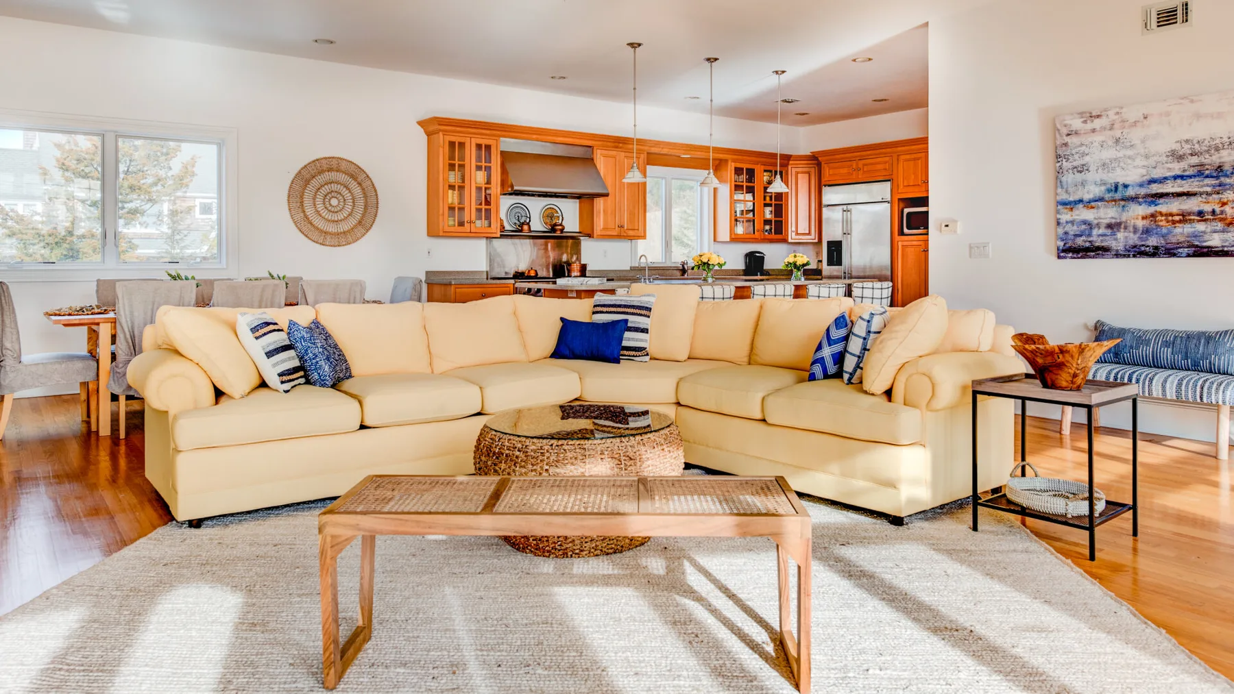 A bright living room with an L-shaped seating area and an open kitchen.