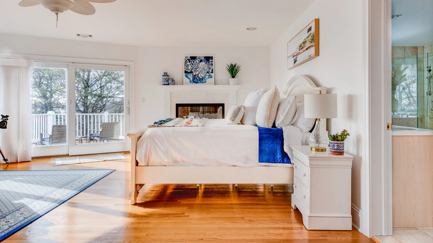 A bright bedroom with a bed beside large windows and a small bedside table.