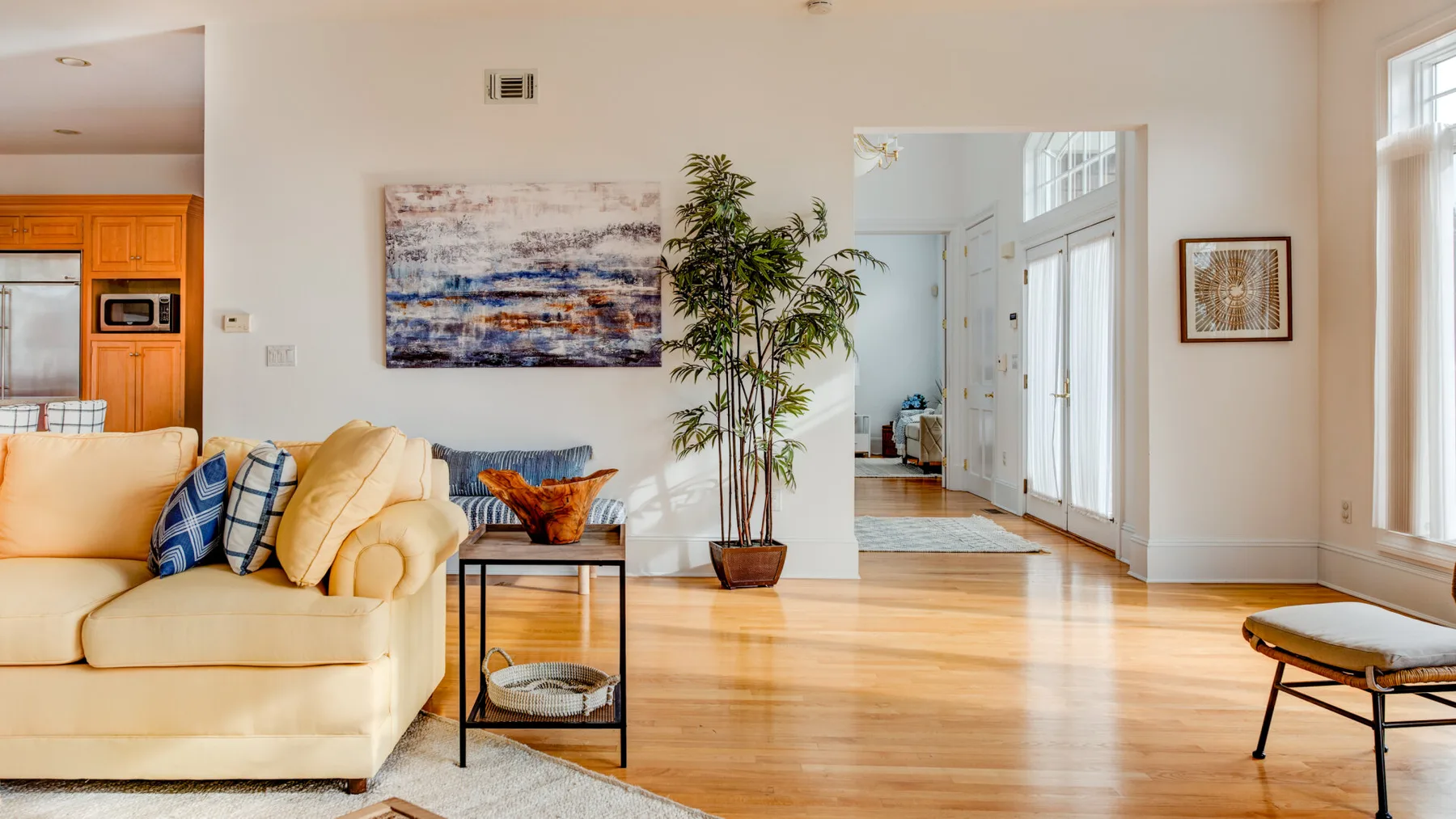 A bright living room with a pale seating area and a large abstract painting.