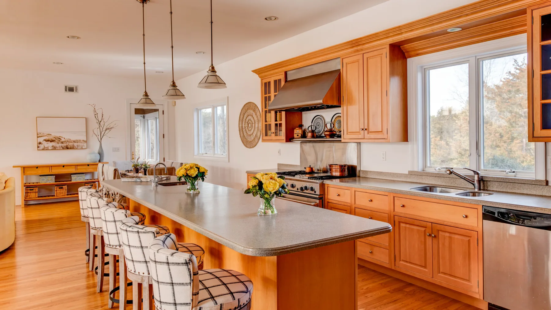 A bright kitchen with a large island, wooden cabinetry, and windows.