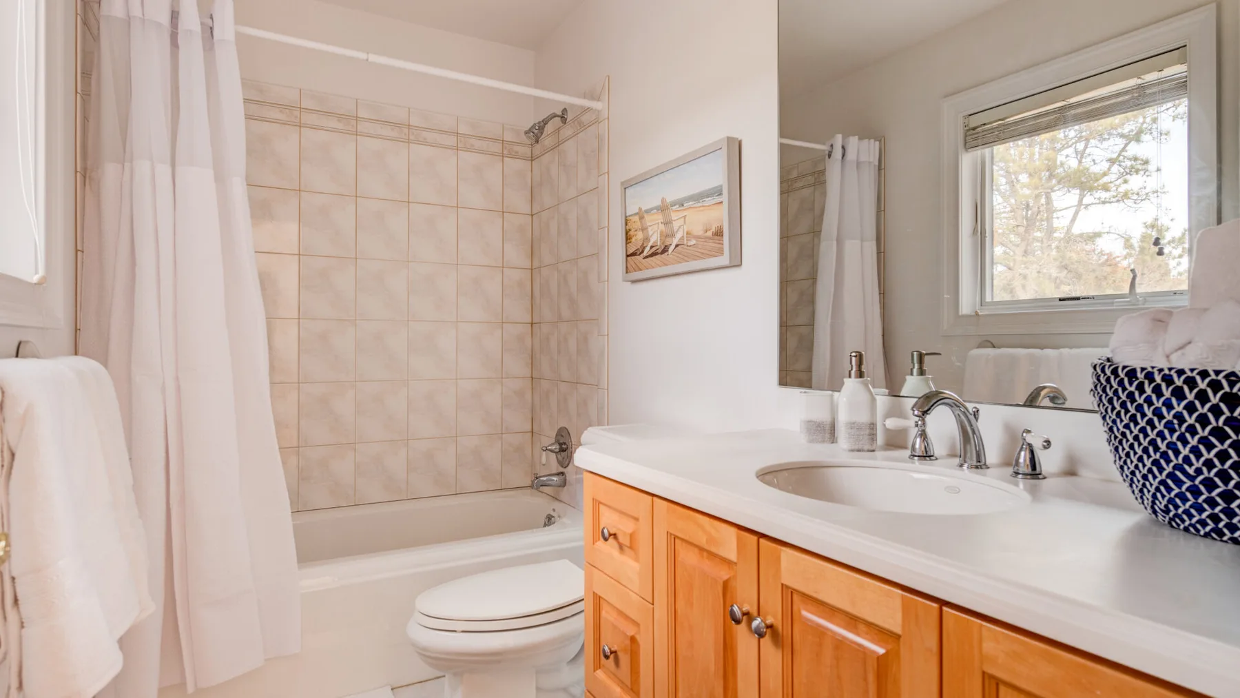 A bathroom with a bathtub, shower curtain, and sink vanity.