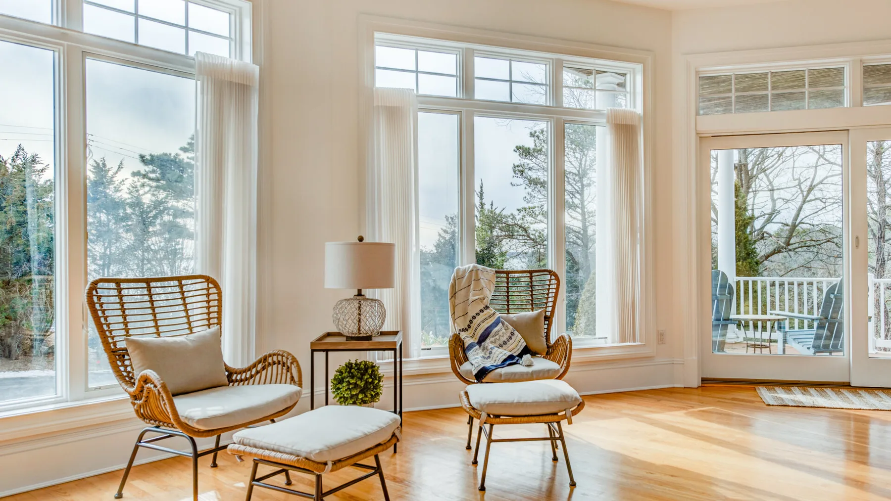 A bright sitting area with wicker seating beside large windows and a glass door.