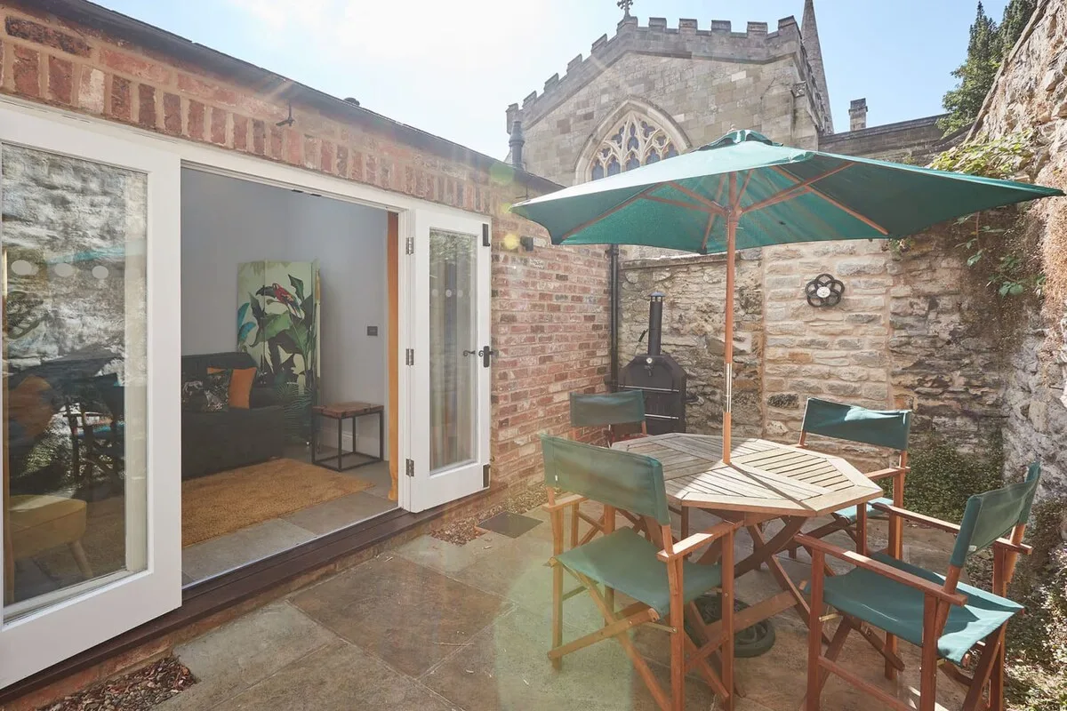 A stone-paved patio with outdoor seating and a large green umbrella.