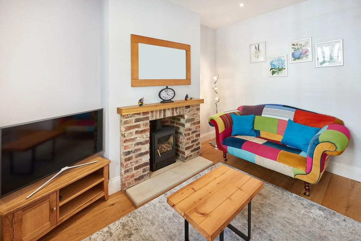 Una sala luminosa con un sofá colorido, una chimenea y una mesa de centro de madera.