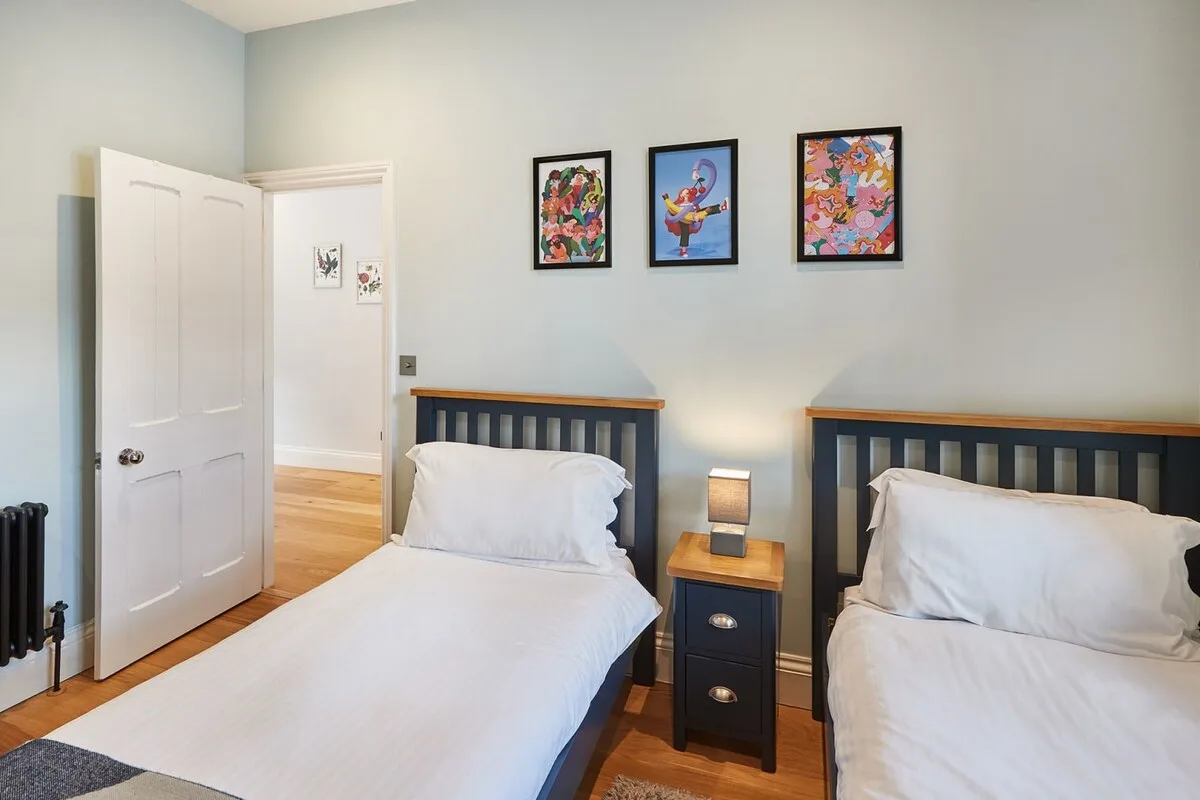 Un dormitorio con dos camas y coloridas obras enmarcadas en la pared.