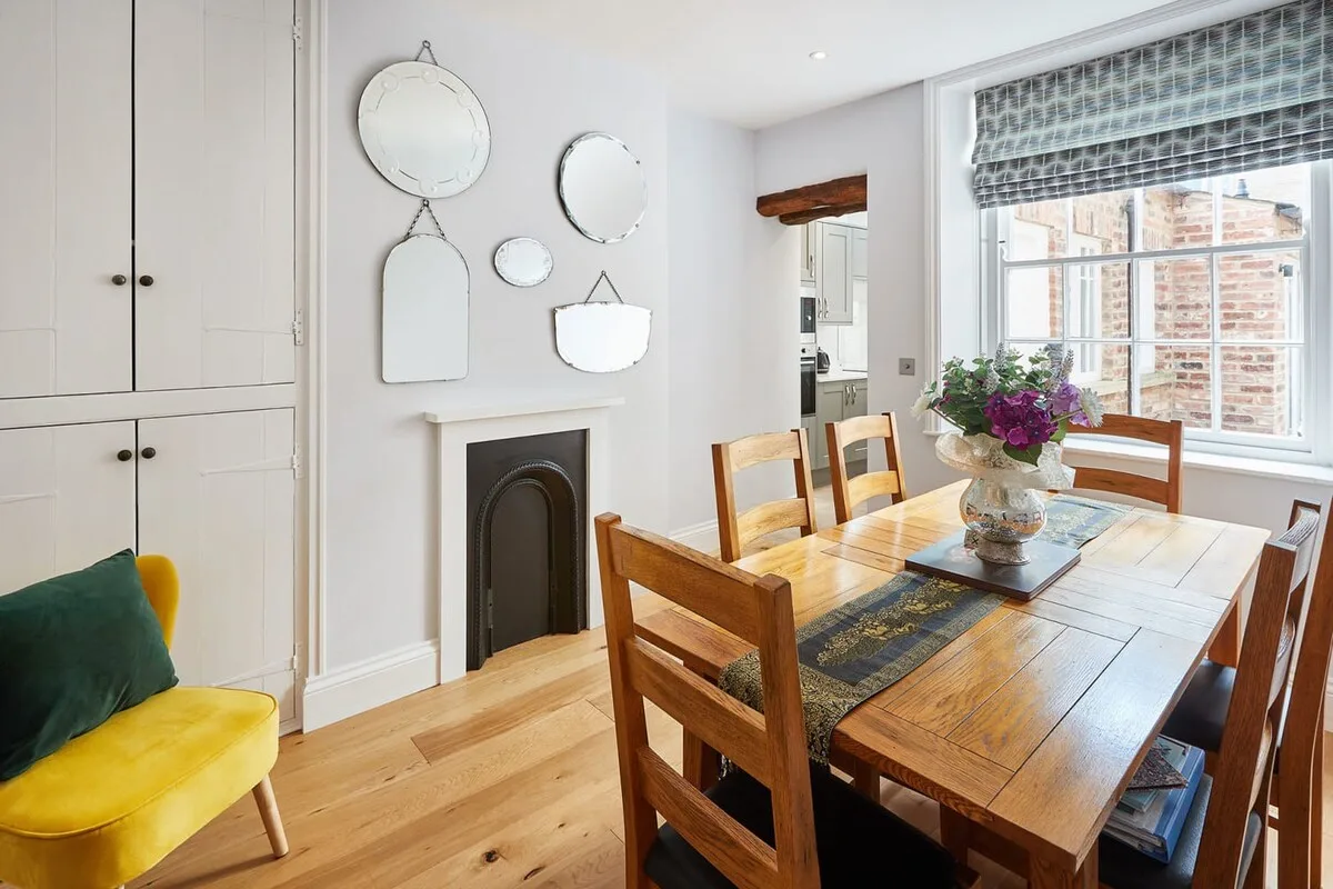 Un comedor luminoso con una mesa y sillas de madera junto a una ventana grande.