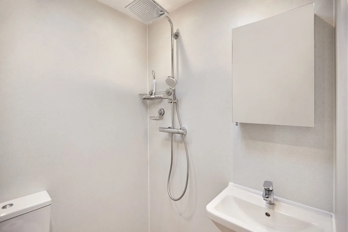 Un baño luminoso con ducha y lavabo de pared.