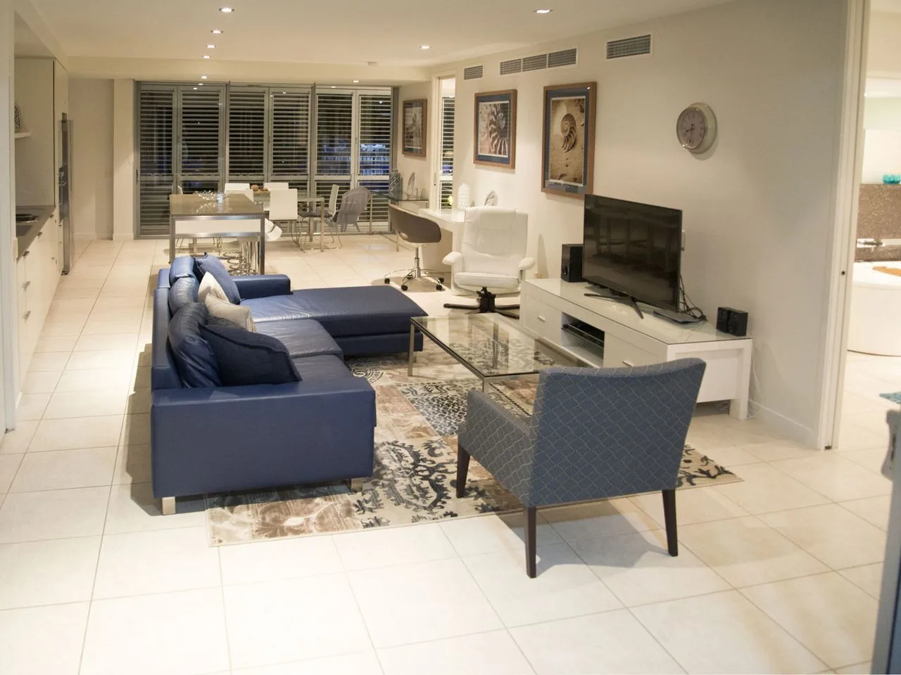 A living room with blue seating, a television, and a dining area.