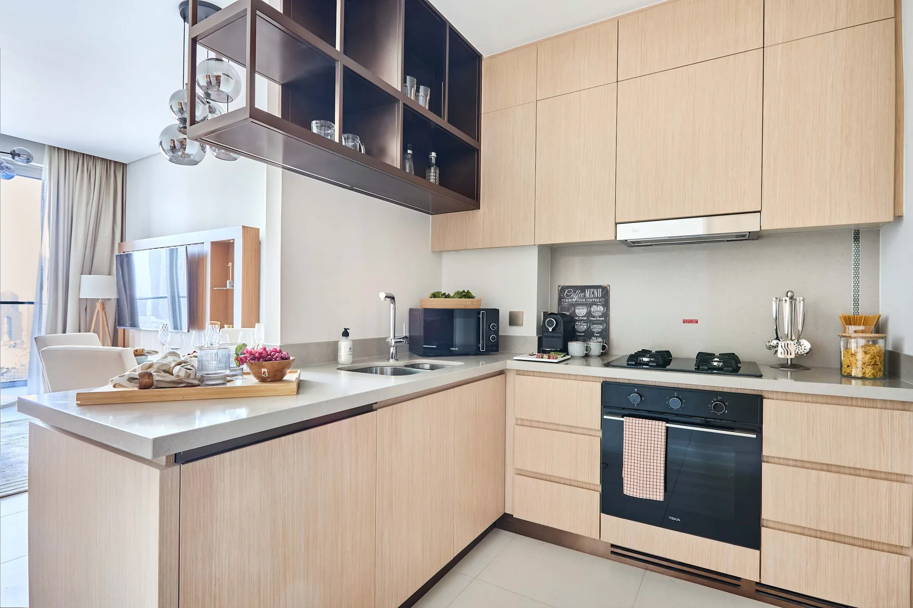 A bright modern kitchen with light wood cabinetry and a central island.