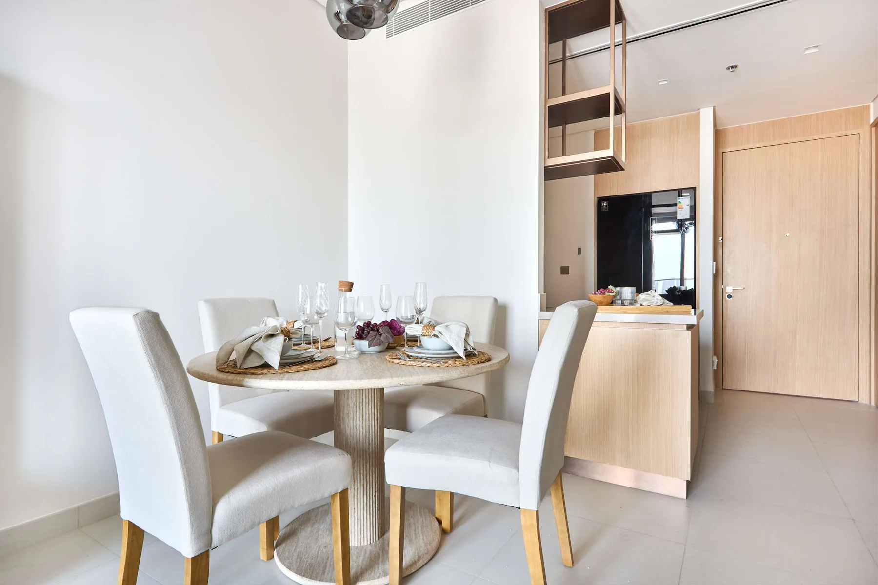 A dining area with a round table set beside a compact kitchen.
