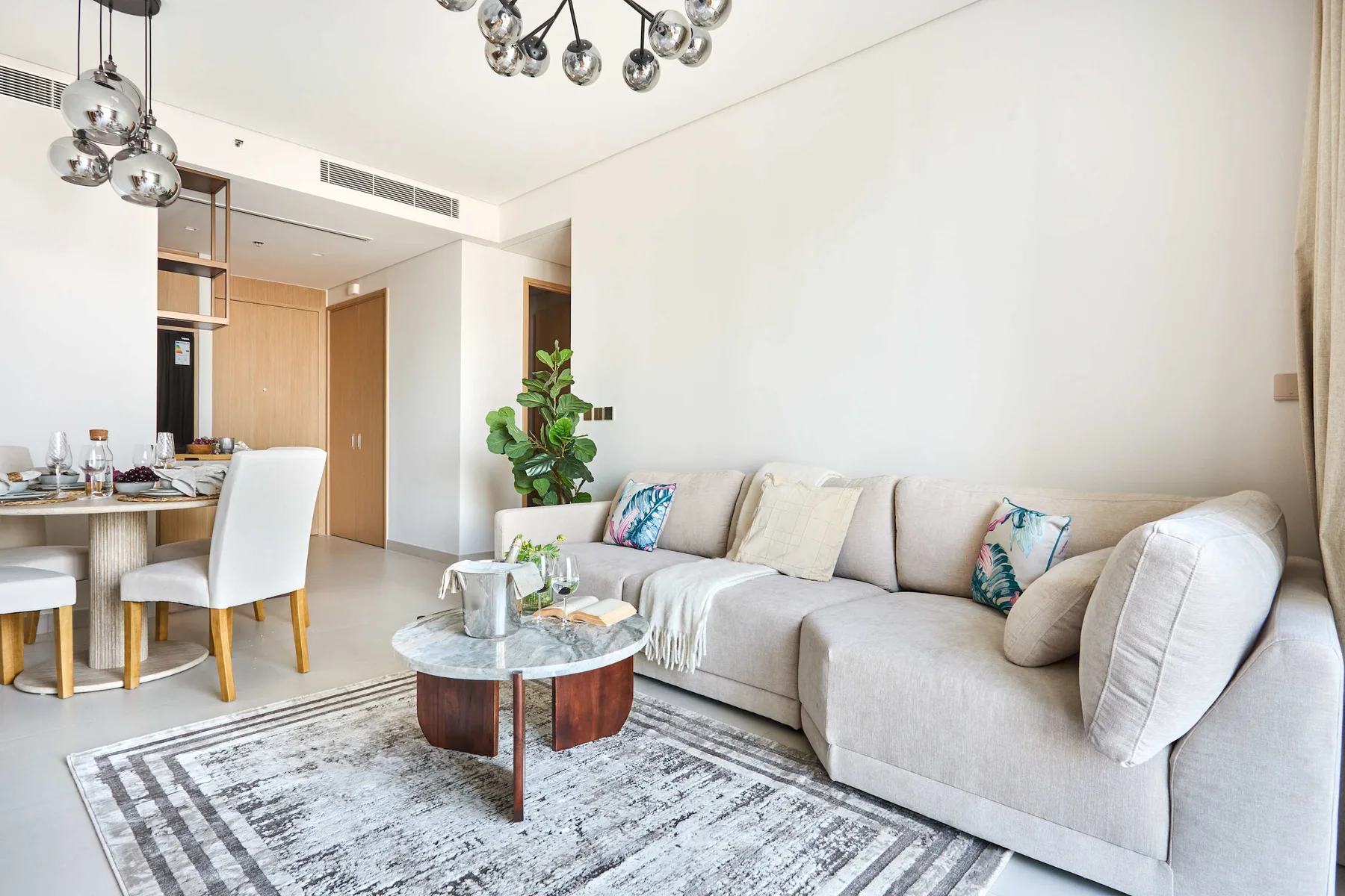 A bright living room with a light-colored seating area and glass coffee table.