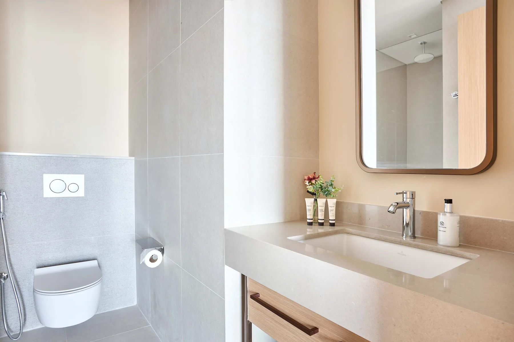 A bright bathroom with a toilet, sink, and wall mirror.