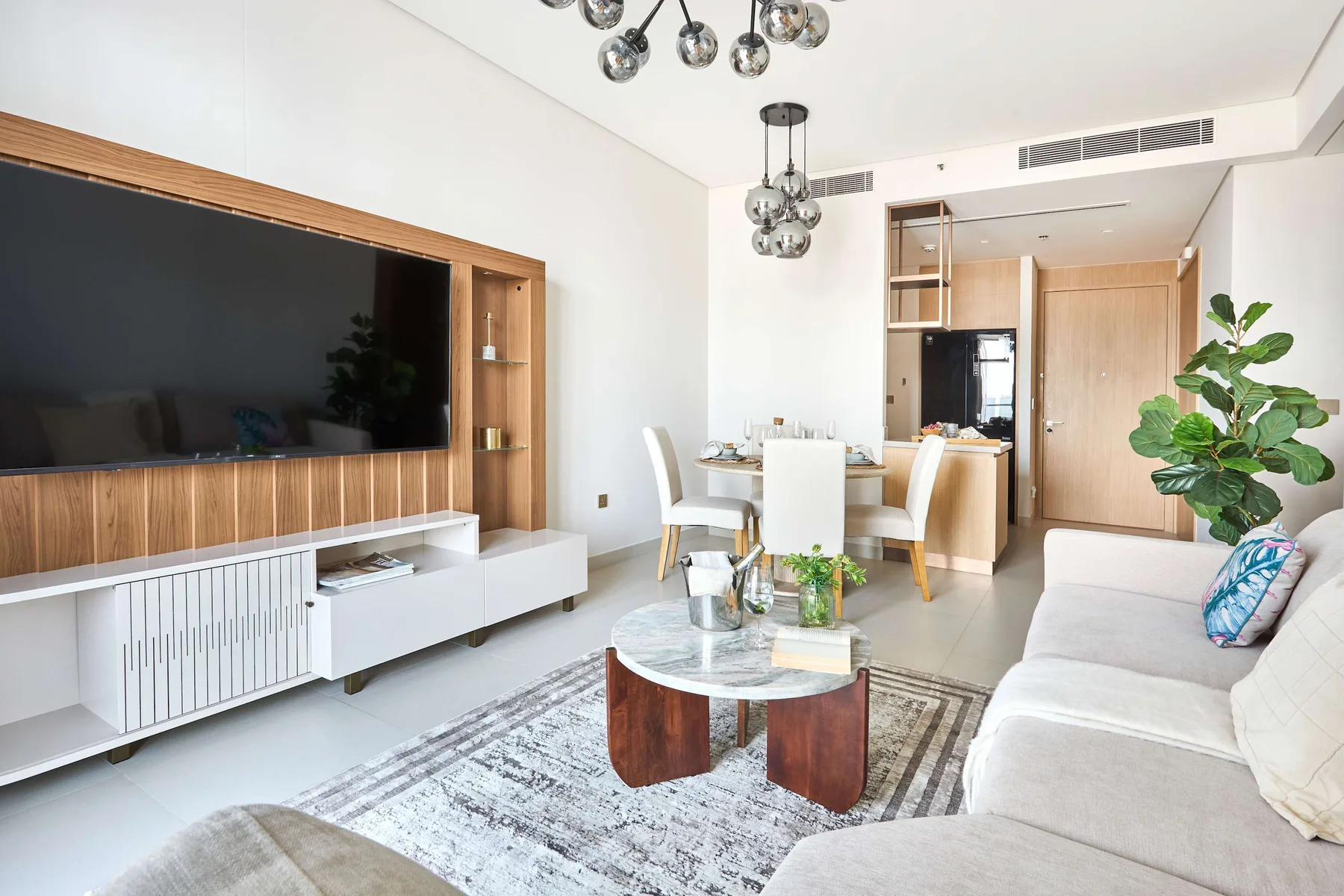 A bright living room with a dining area and a large television.