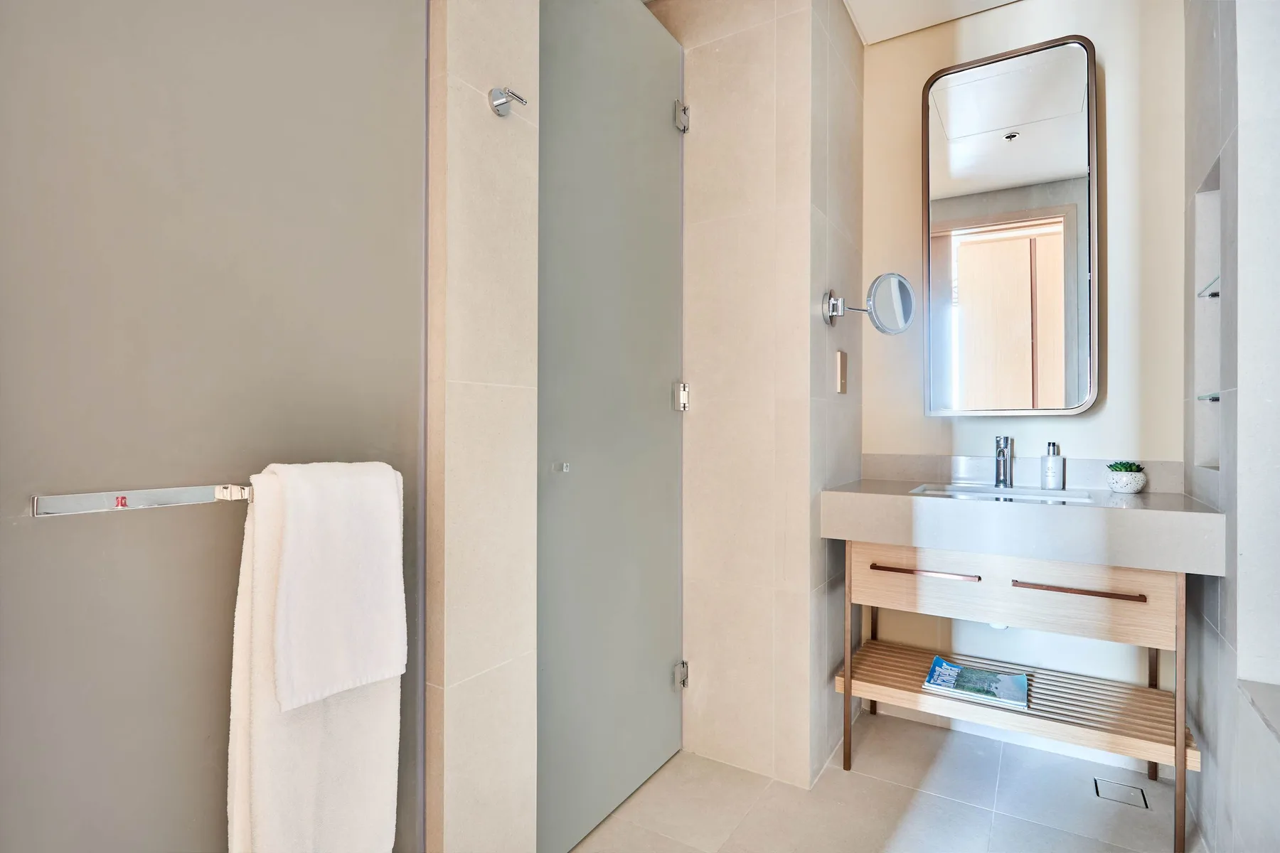A bright bathroom with a glass shower and a vanity beneath a mirror.