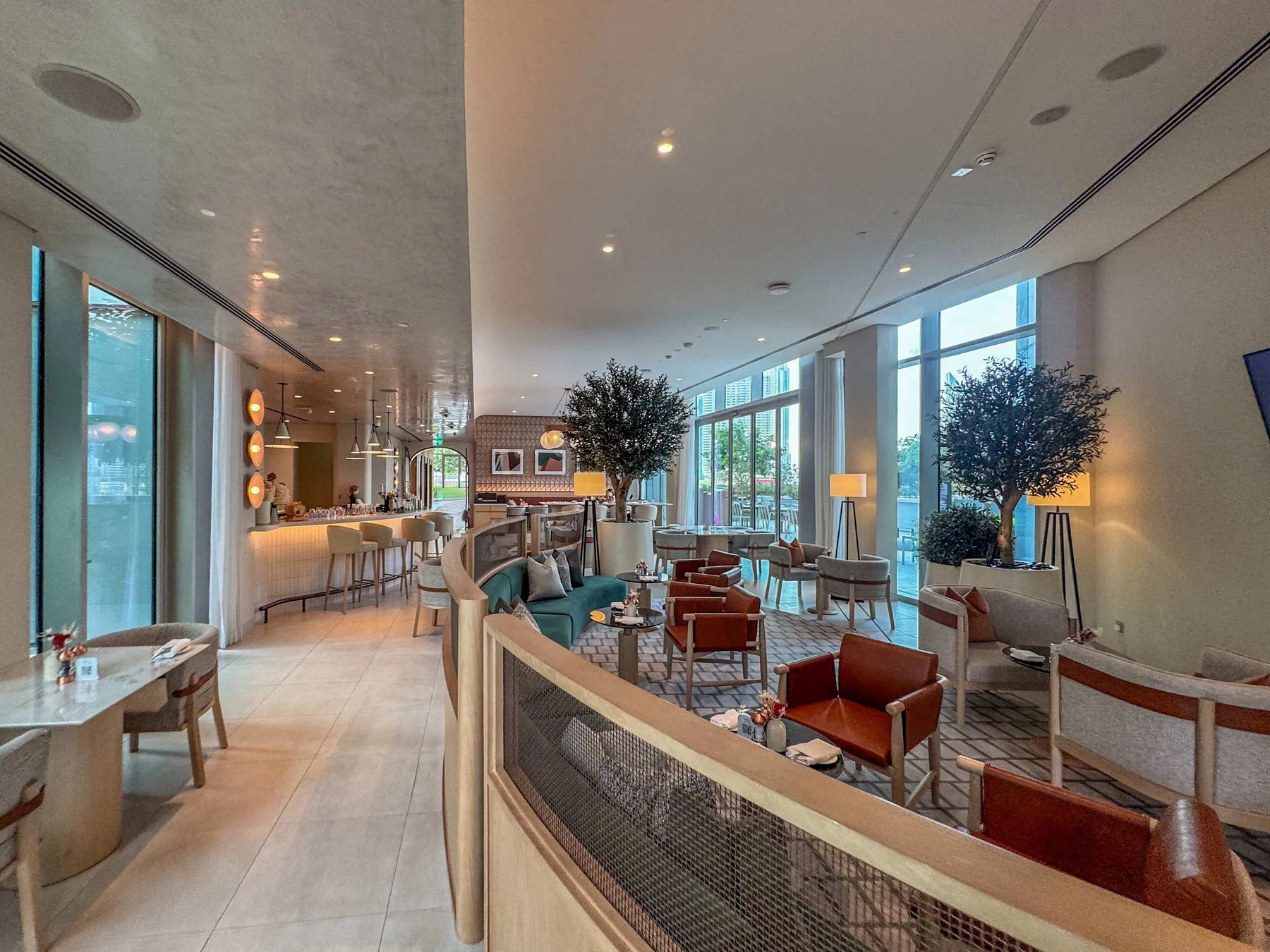 A bright lounge with seating, large windows, and a counter in the background.
