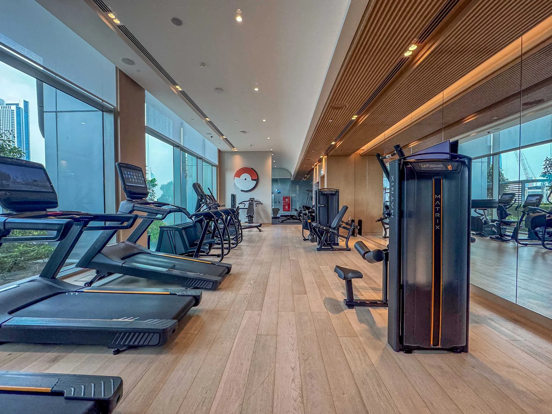 A gym with exercise machines and floor-to-ceiling windows.