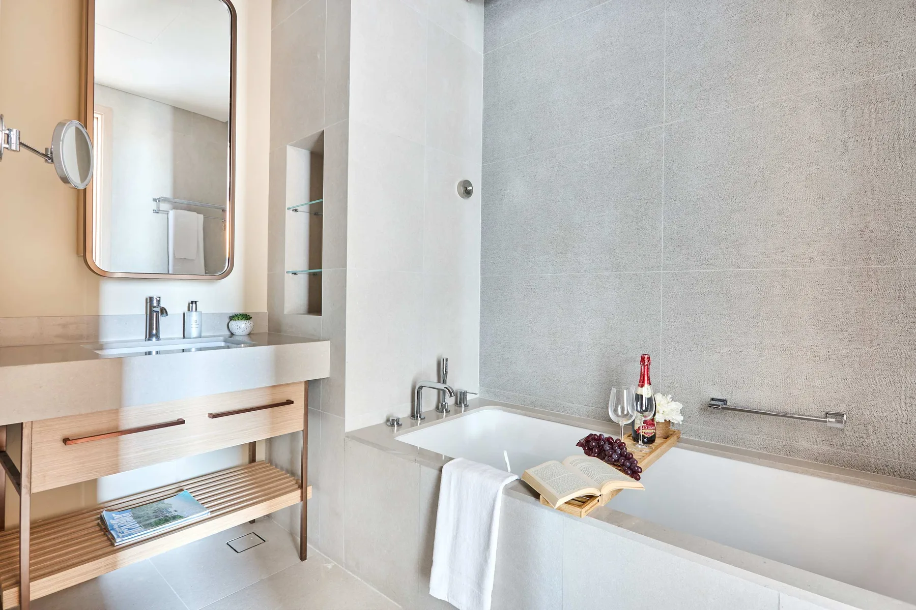 A bright bathroom with a bathtub beside a vanity and mirror.