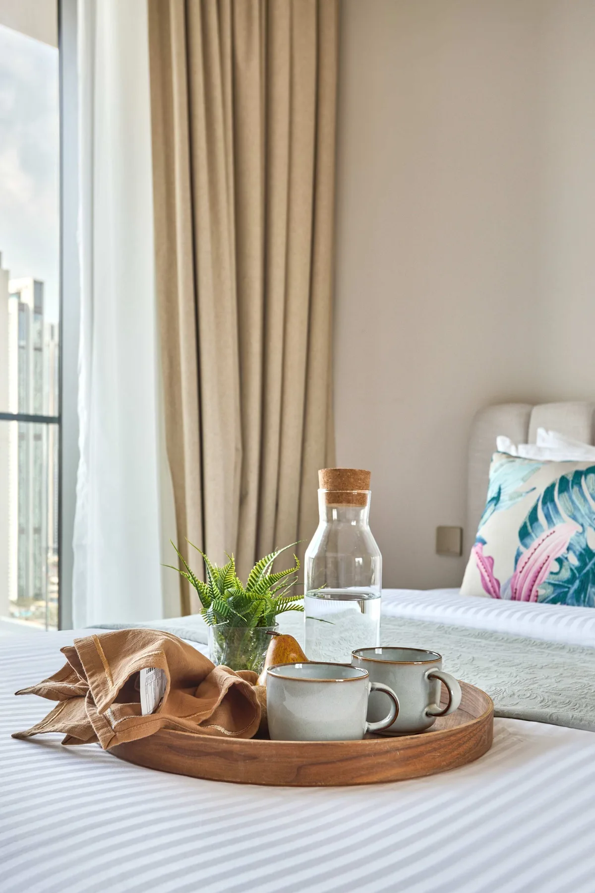 A bedroom with a bed beside a window and a tray on the bedding.