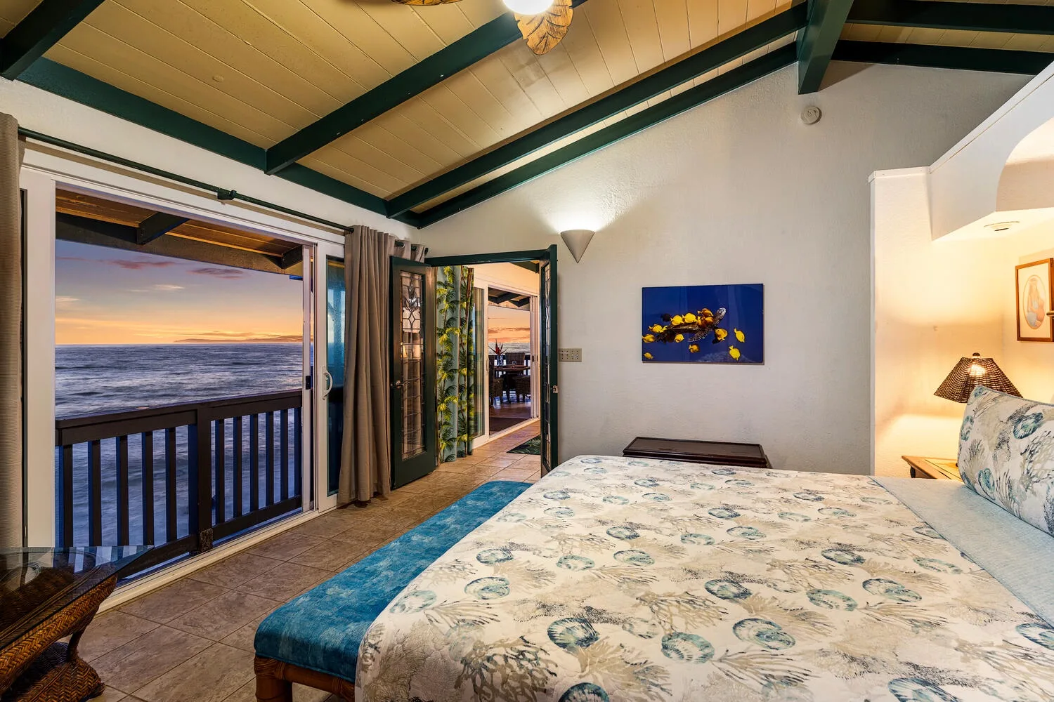 Un dormitorio da a un balcón con vistas al océano al atardecer.