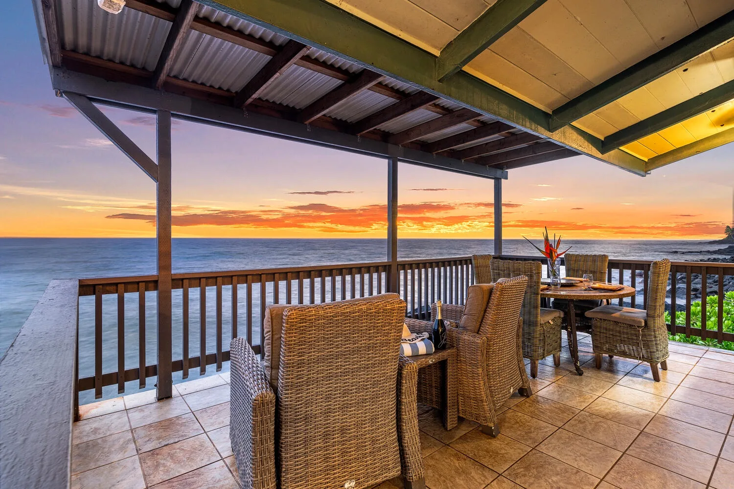 Un patio cubierto con asientos de mimbre da al mar al atardecer.