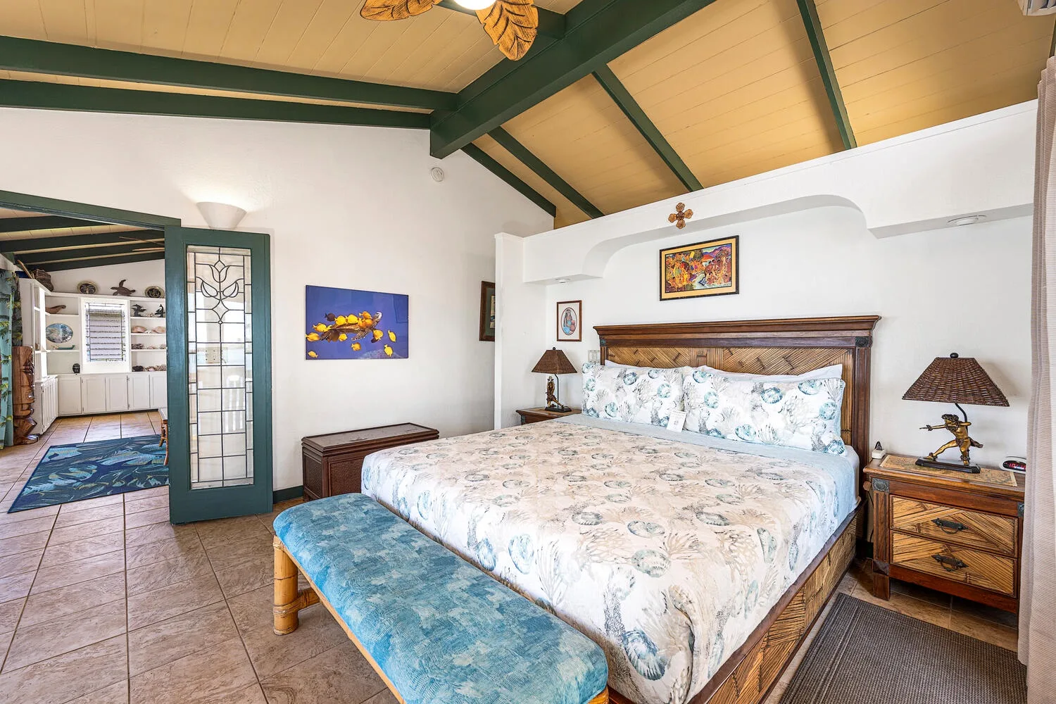 Un dormitorio con una cama estampada y un banco azul tapizado a sus pies.