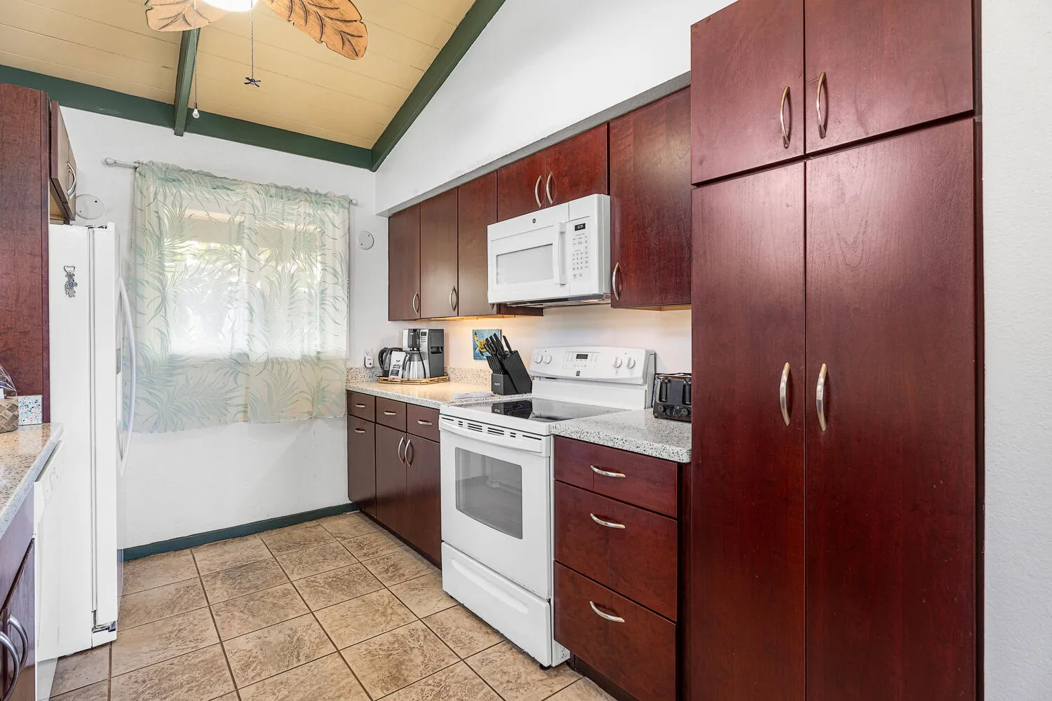 Una cocina con gabinetes de madera oscura, una estufa blanca y una ventana.
