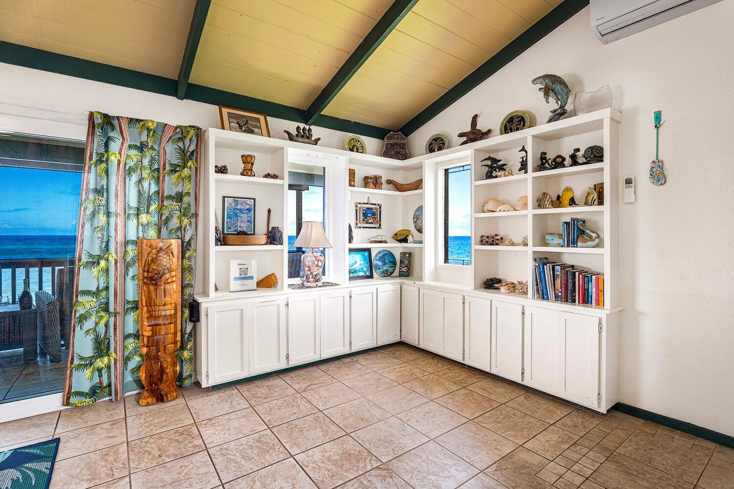 Una habitación luminosa tiene armarios y estantes blancos empotrados con objetos decorativos.