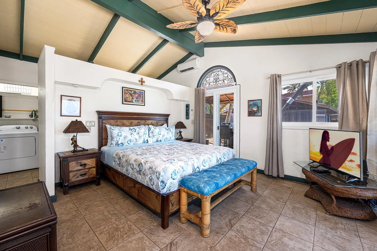 Un dormitorio con una cama grande, un banco azul y un ventilador de techo.
