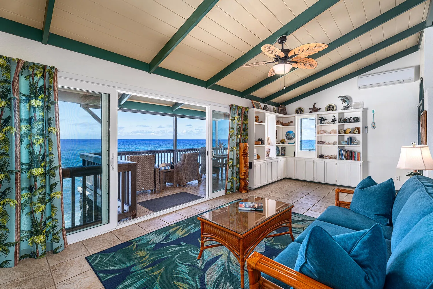 Una sala de estar se abre a un balcón con vistas al mar y asientos azules.