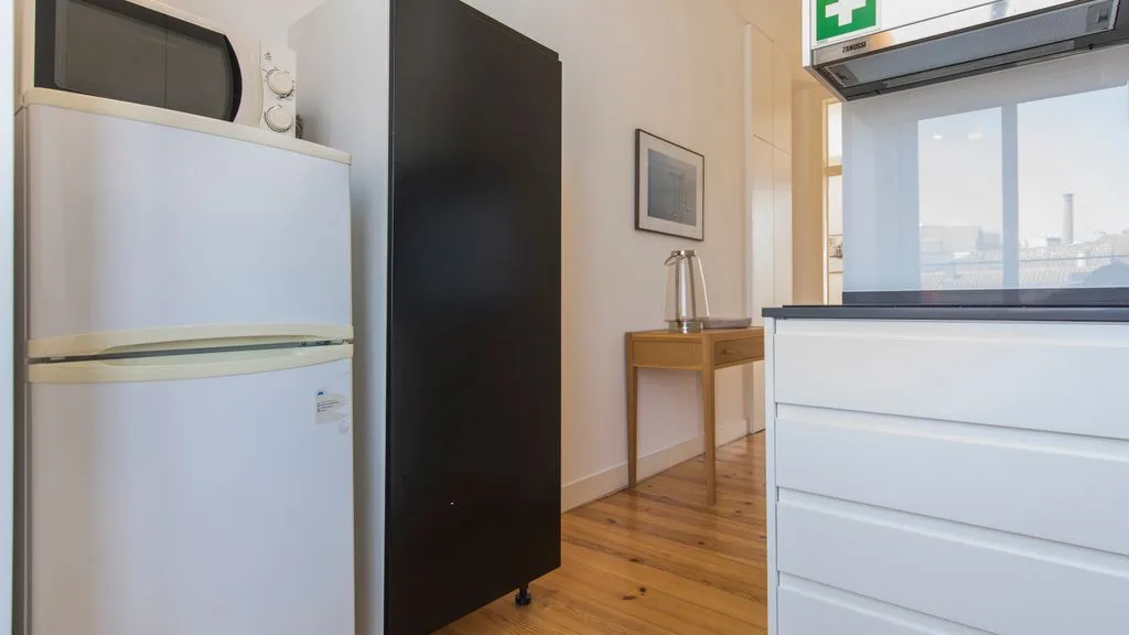 Una cocina compacta con electrodomésticos blancos y suelo de madera.