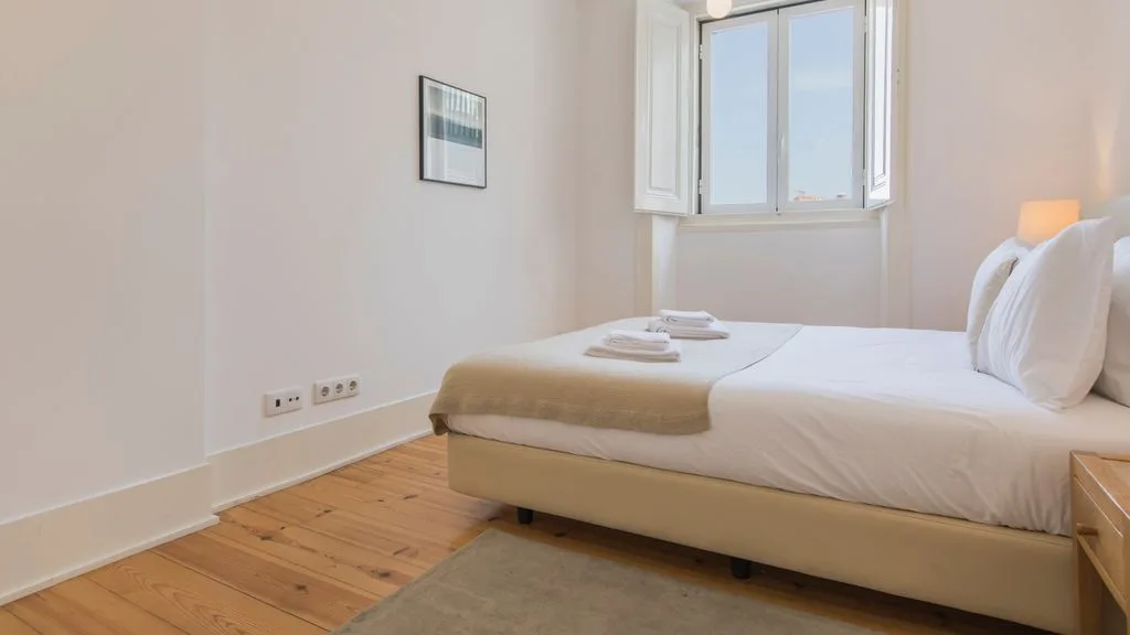 Un dormitorio luminoso con una cama junto a una ventana.
