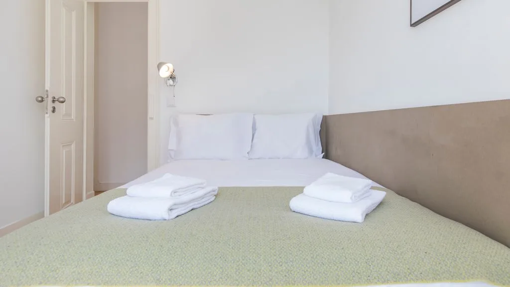 Un dormitorio con una cama bien hecha y toallas dobladas.