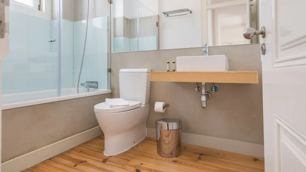 Un baño luminoso con bañera, inodoro y lavabo de madera.