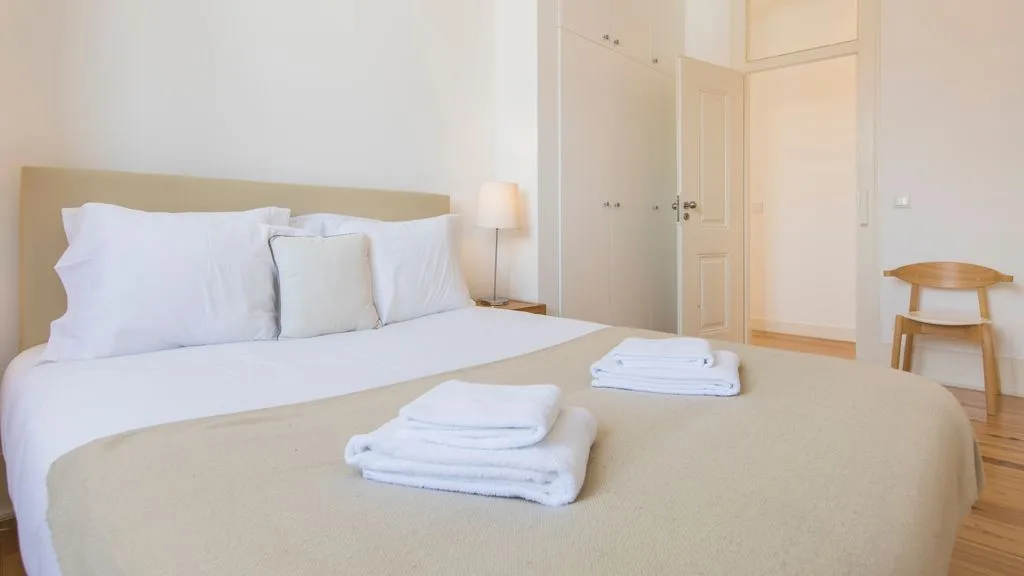 Un dormitorio con una cama bien arreglada y toallas dobladas.