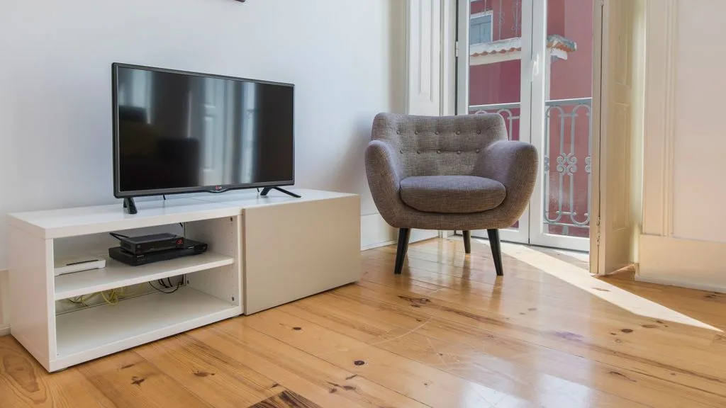 Una sala de estar con un televisor, un asiento y una puerta de vidrio.