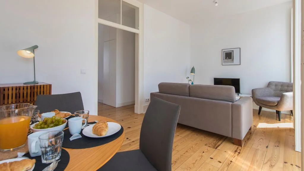 Una sala de estar con asientos alrededor de una mesa baja y un televisor.