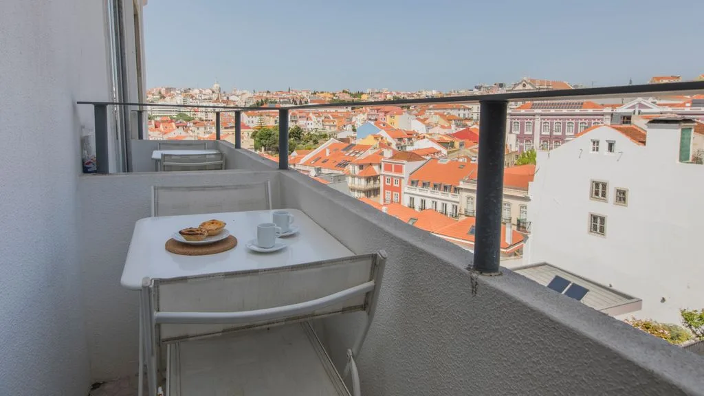 Una zona de comedor en el balcón tiene vistas a tejados rojizos de la ciudad.