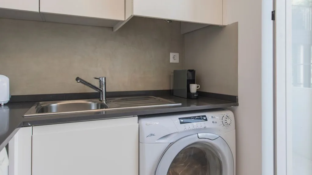Una cocina compacta con fregadero, encimera y lavadora.