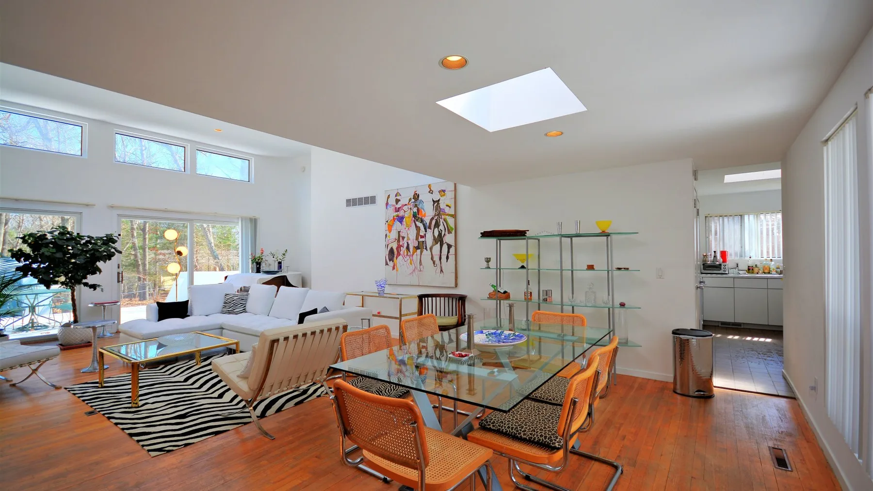 A bright open-plan living and dining area with glass dining table and seating.