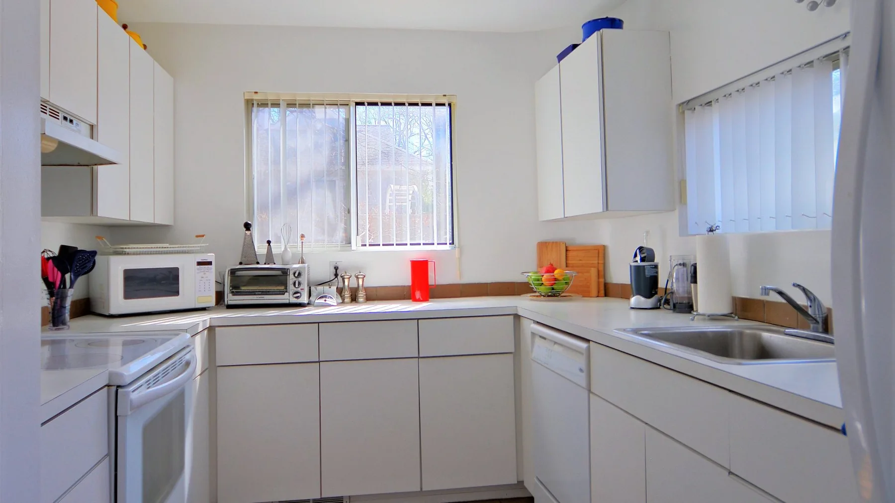 A bright kitchen with white cabinets, a countertop, and a sink.