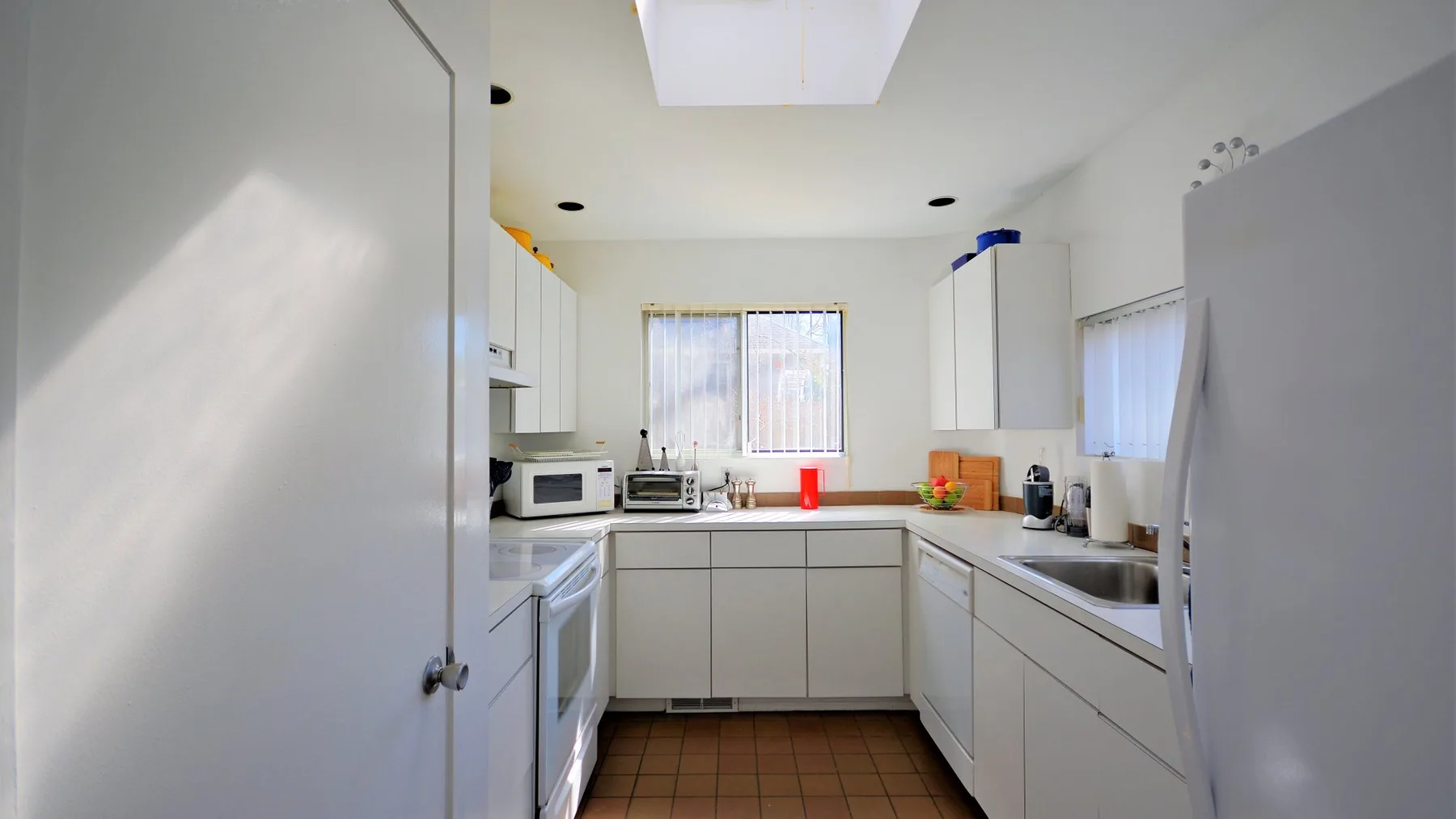 A bright kitchen with white cabinets and a countertop around the sink.