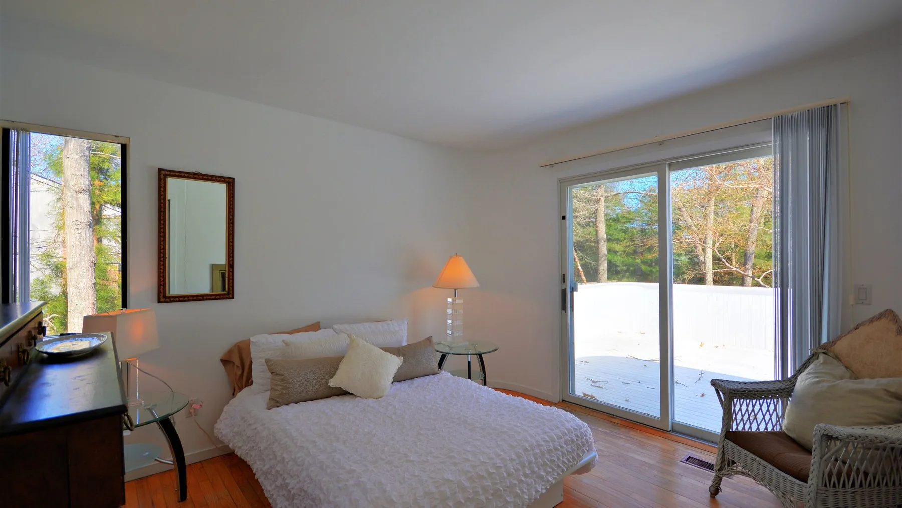 A bedroom with a bed, a small table, and sliding glass doors opening onto a snowy patio.