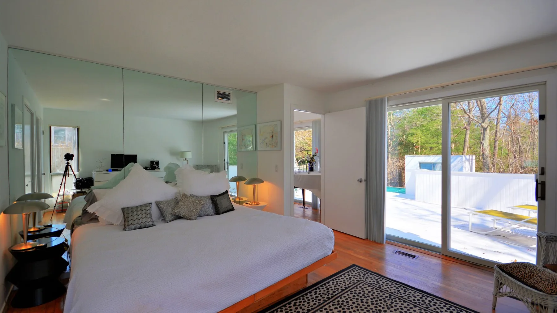 A bedroom with a large bed and sliding glass doors opening onto a patio.