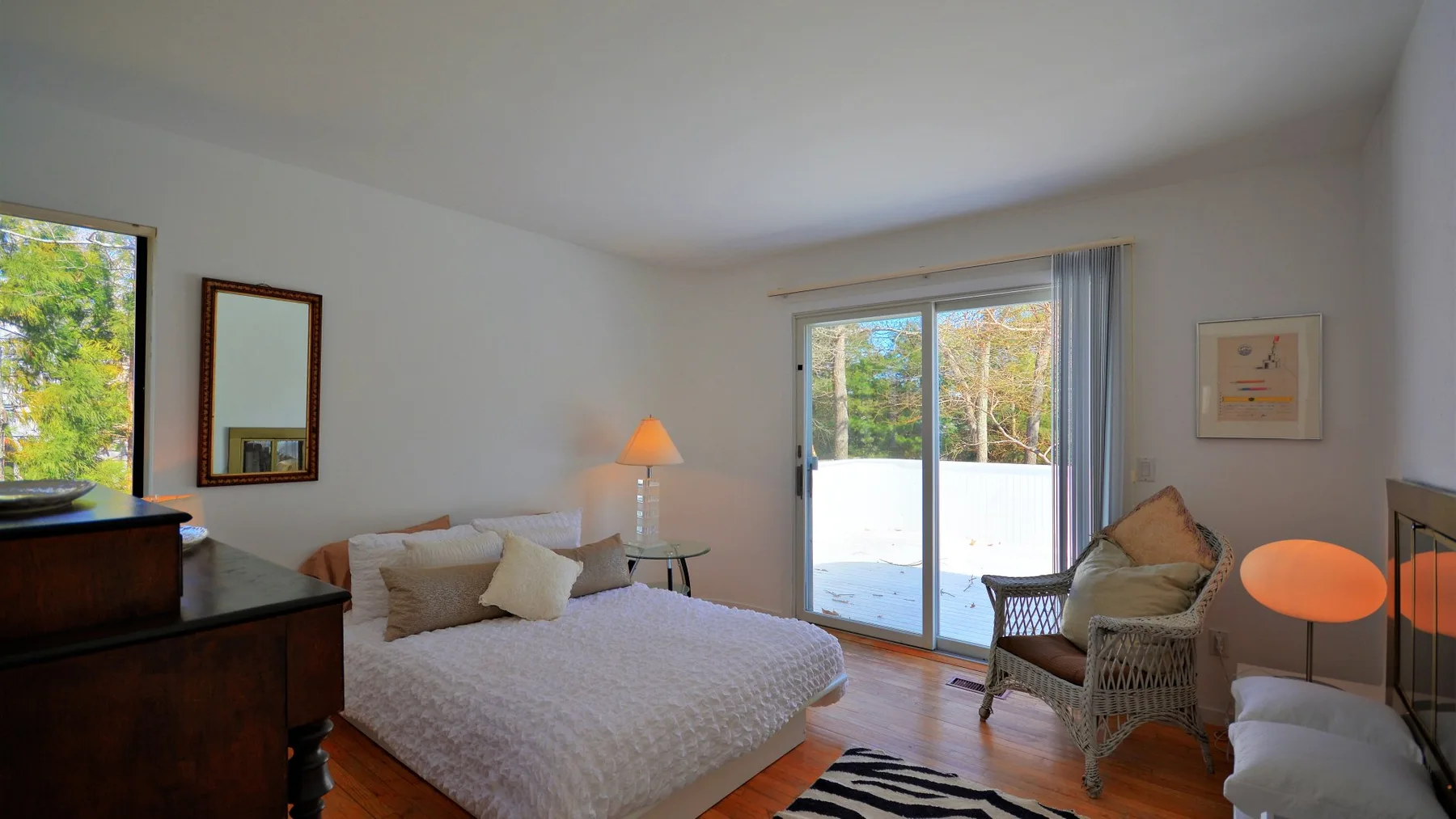 A bright bedroom with a bed and sliding glass doors opening onto a balcony.