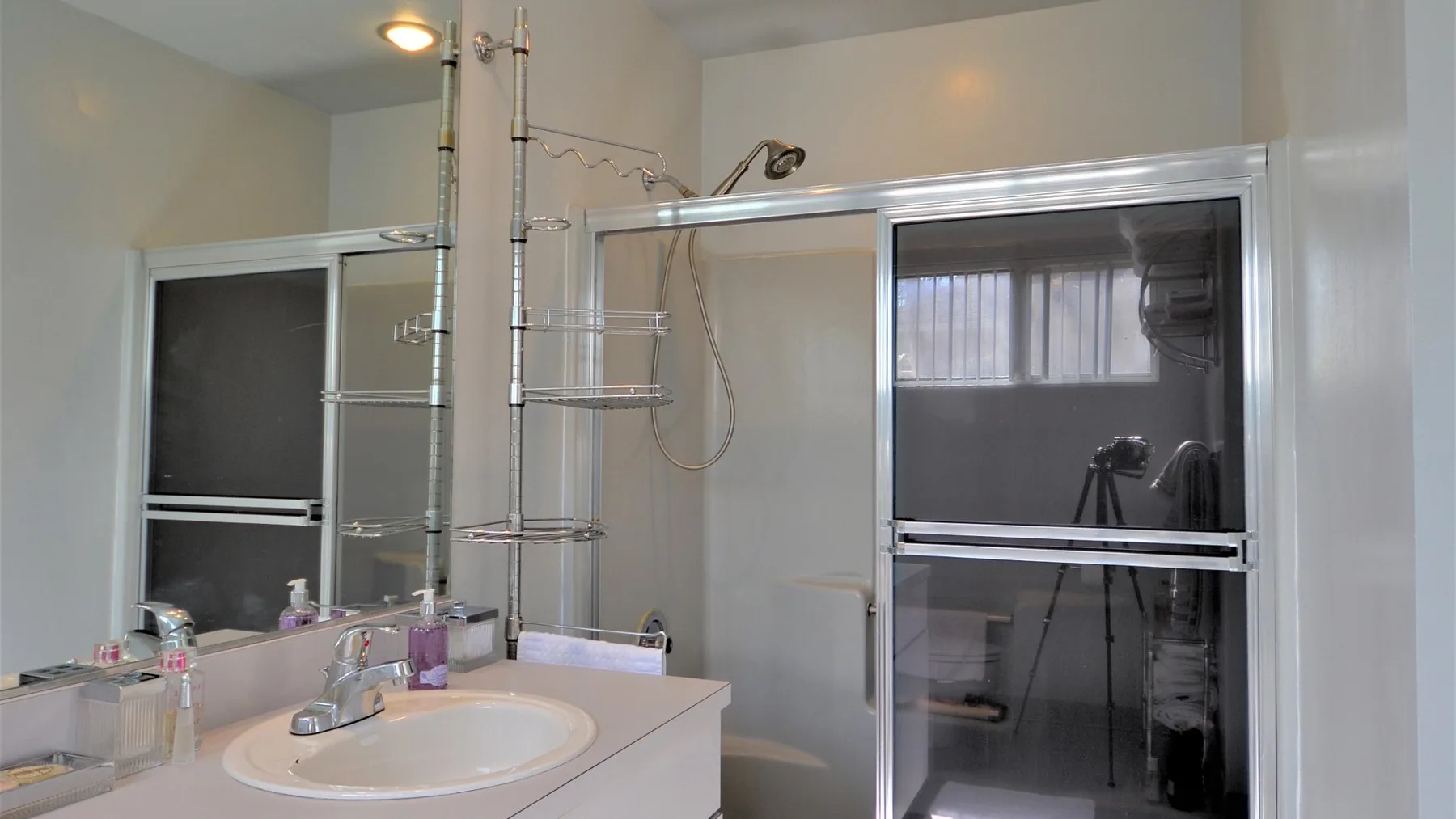 A bathroom with a sink and glass-enclosed shower.