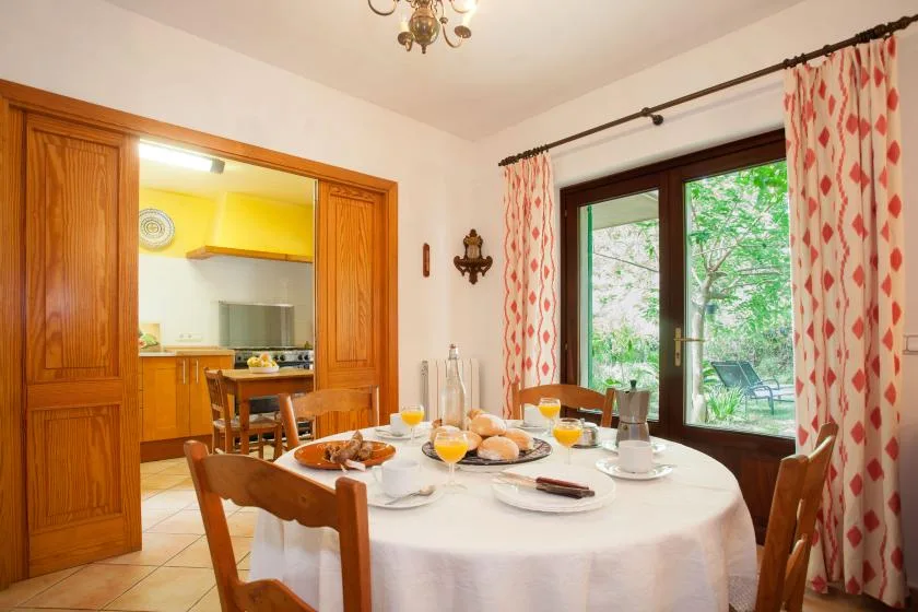 A dining area with a set table beside a large window overlooking greenery.