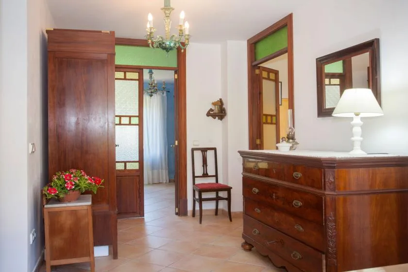 A bedroom dressing area with wooden furnishings and a doorway to an adjoining room.