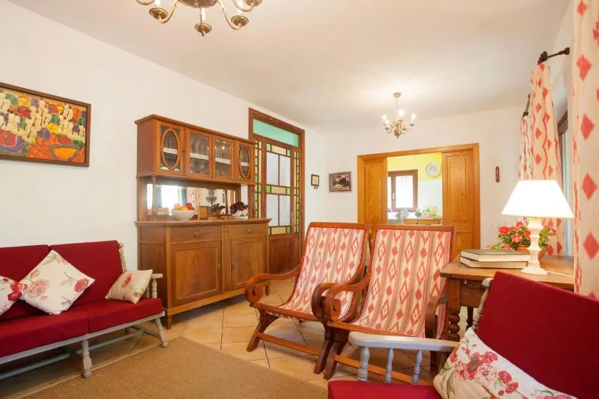 A living room with patterned seating, wooden cabinets, and a dining table.