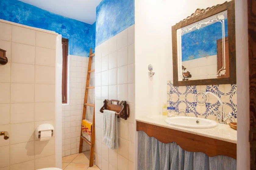 A tiled bathroom with a sink, wall mirror, and blue decorative accents.